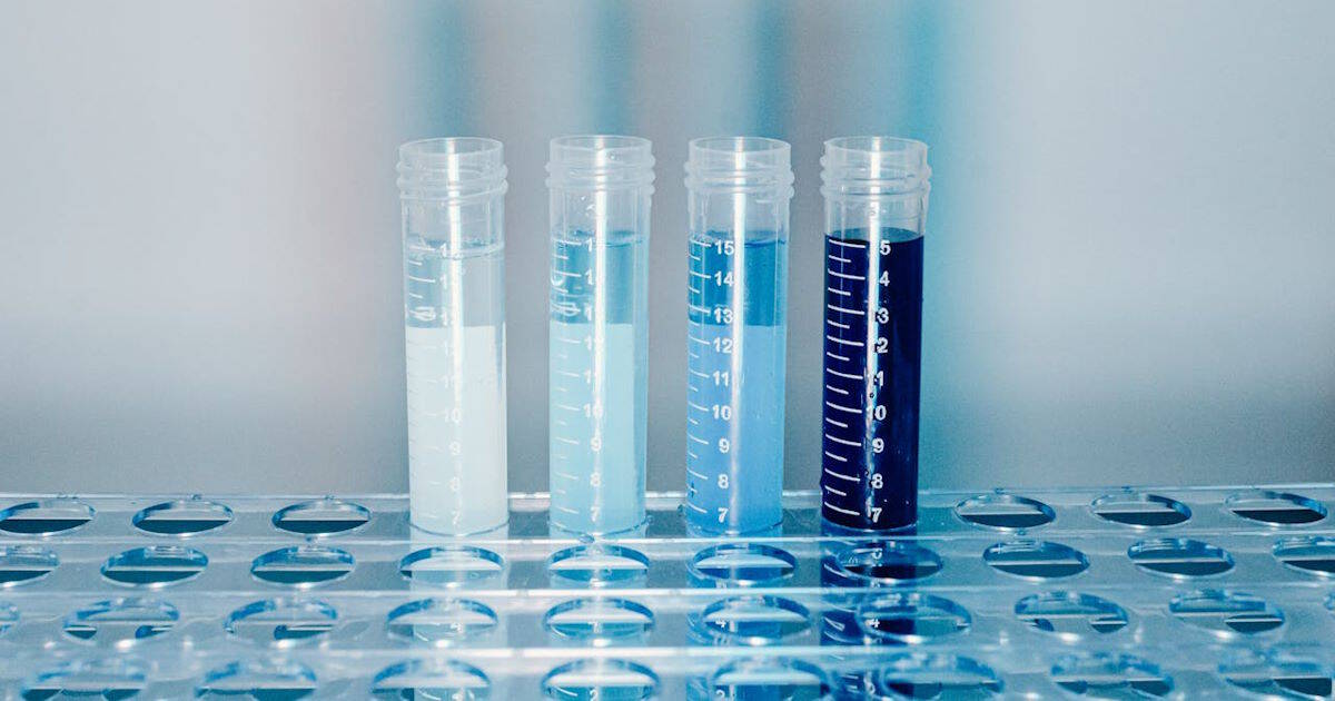Graduated laboratory test tubes with blue liquid solutions set in a rack for MOTS-c mitochondrial peptide research